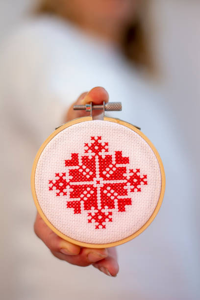 Woman holding hand made cross stitch folk Christmas decoration ornament embroidery on plywood. Nordic snowflakes. stock photo