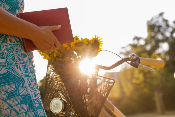자전거 바구니에 책을 포장하는 여성 - book reading dress women 뉴스 사진 이미지