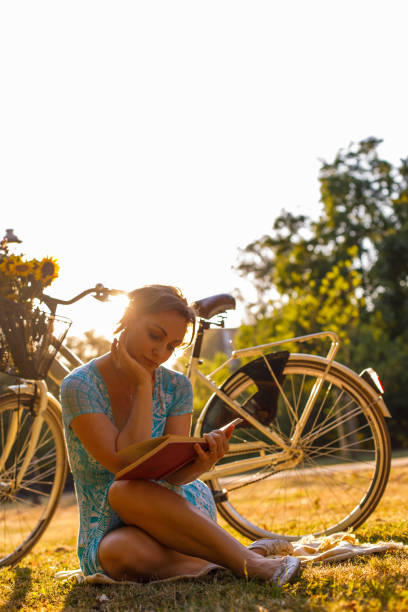 istock Mature woman sitting in the meadow, reading a book 1343603830