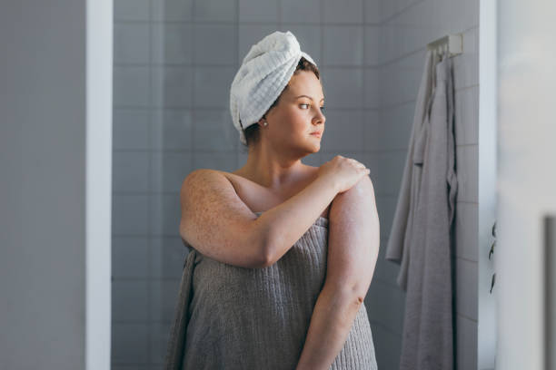 Beautiful Plus Size Woman Applying Body Lotion after Taking a Shower A young overweight woman applying body lotion after a shower in the morning hand towels stock pictures, royalty-free photos & images
