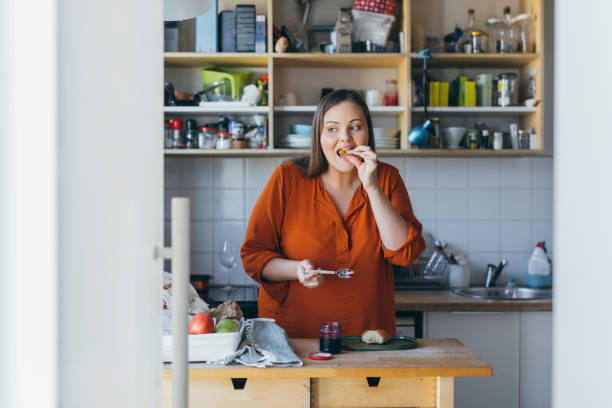 donna happy plus size che ha fatto colazione in cucina - preserves croissant breakfast food foto e immagini stock