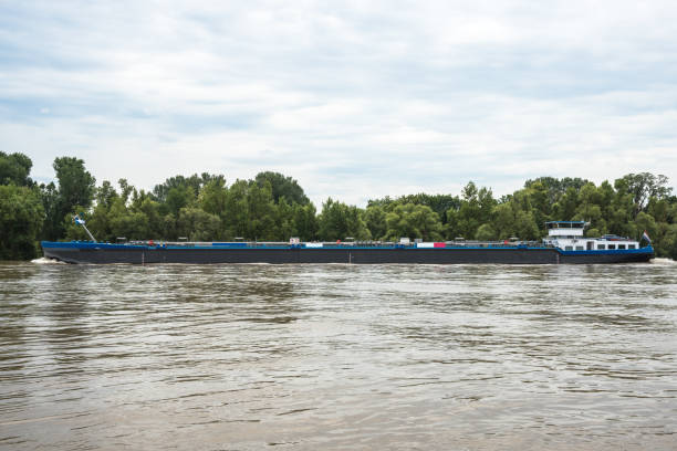 istock Tanker barge sailing up a large river on a cloudy summer day 1343612649