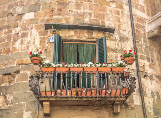 An elegant wrought-iron balcony of an old medieval house decorated with flowers