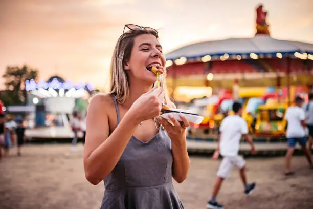 Photo of Cute Woman eating small donuts at the Funfair