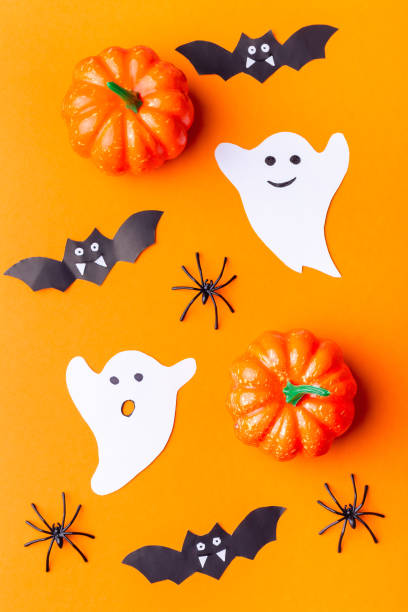 istock Halloween background with spiders, ghosts, bats and pumpkin on orange paper, vertical, top view 1343616472