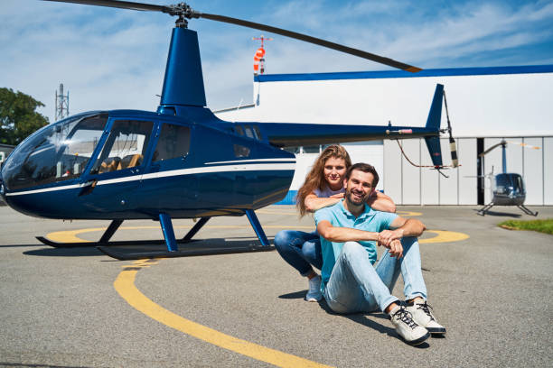 Joyous young couple posing against private helicopter