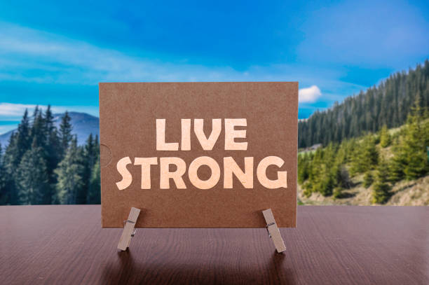 Live strong text on card on the table with mountains Live strong text on card on the table with mountain valley background. lance armstrong foundation stock pictures, royalty-free photos & images