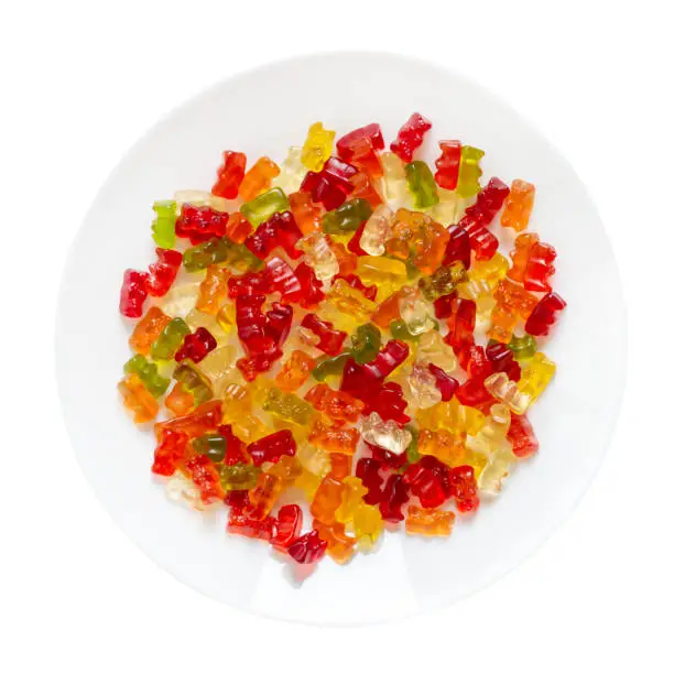 Photo of Jelly bears on a plate isolated on a white background. Traditional fruit gummies. Top view.