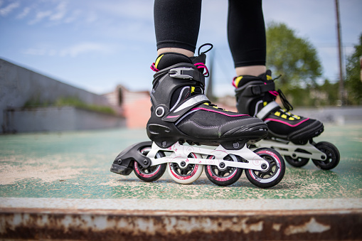 A woman rides rollerblades in the park. Prepares for rollerblading. Enjoys a nice day.
