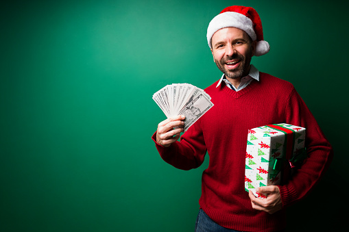 Super happy man buying presents and holding a lot of money to spend during Christmas