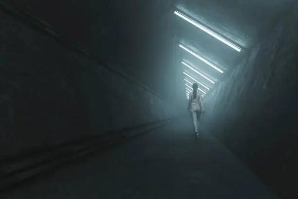 Photo of Woman walking in dark concrete corridor