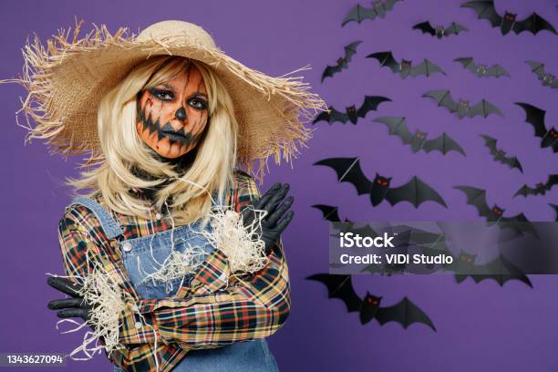 Young Creepy Woman With Halloween Makeup Mask In Scarecrow Costume Cover  Painted Face With Straw Hat Brim Isolated On Plain Dark Purple Background  Studio Portrait Celebration Holiday Party Concept Stock Photo 