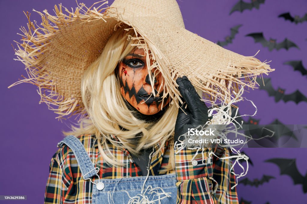 Young Creepy Woman With Halloween Makeup Mask In Scarecrow Costume