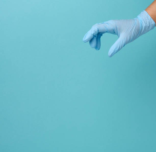istock Doctor's hand in a blue medical glove holds an object on a blue background 1343633395