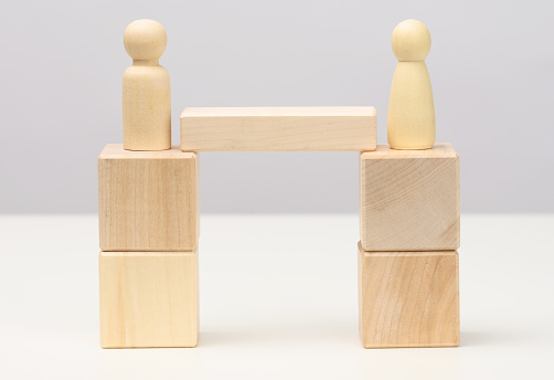 wooden figures stand on the bridge from the sides opposite each other, concept of finding a compromise, constructive dialogue, business opponents