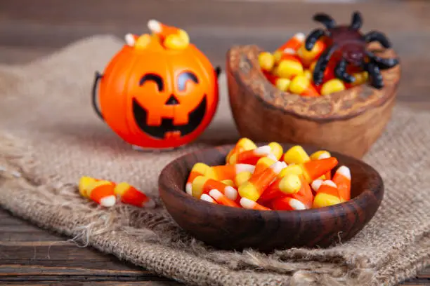 Photo of Bowls of Halloween Candy Corns and Jack O' Lantern on Wooden Rustic Table