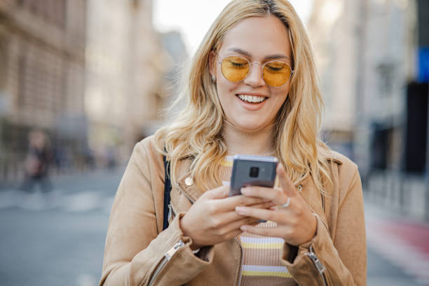 istock Blonde hair woman using mobile phone and walking 1343635690