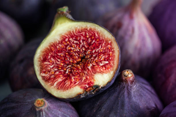 Fig cut in half lying on a ripe fig Heap of tasty organic figs fig stock pictures, royalty-free photos & images