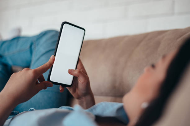 istock Young woman using smartphone while lying on the couch at home 1343648221