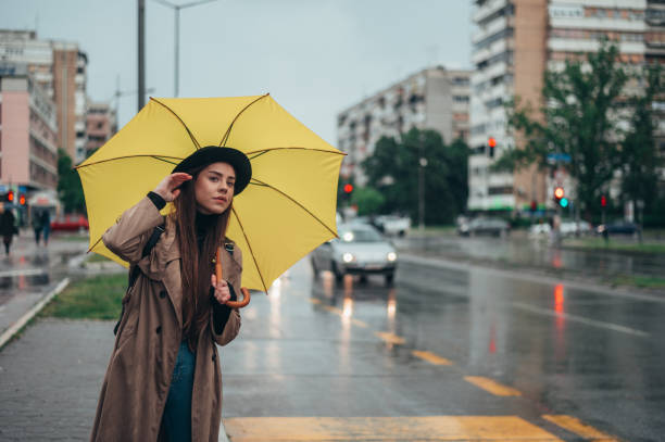 istock Young beautiful woman holding yellow umbrella while calling for a cab 1343648334