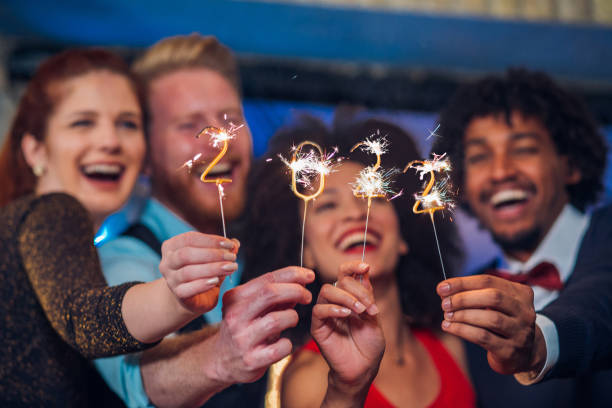 Smiling people holding sparklers Joyful young people holding sparklers in a club 2022 photos stock pictures, royalty-free photos & images