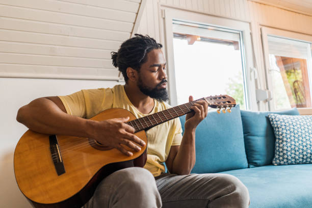 istock Young African American man playing guitar at home. 1343658080