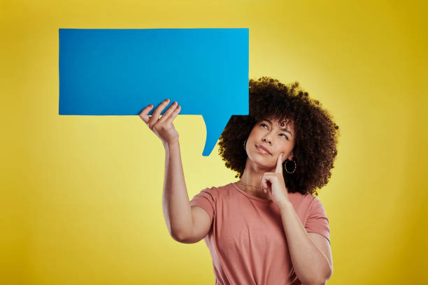 foto de estudio de una atractiva joven sosteniendo una burbuja de habla sobre un fondo amarillo - thought bubble speech bubble decisions thinking fotografías e imágenes de stock