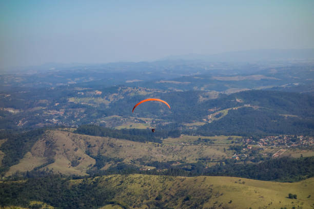 istock Paraglider flying over green forest mountains on a sunny clear day 1343672865