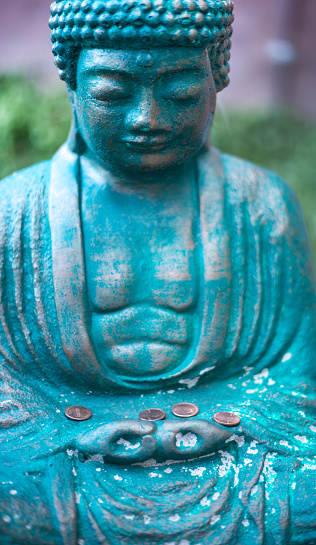 Green Buddha Statue with Pennies Close-Up