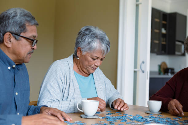 istock Two diverse female and male friends sitting at table and doing puzzles 1343681292