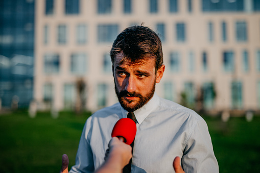 Good looking man having an interview for TV, asked a few questions on the street by the journalist. TV media crew asking a businessman about the financial crisis.