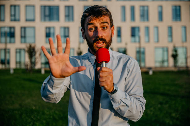 We’re starting in five, four… A spontaneous photo of a handsome bearded young adult journalist, standing in front of the camera, outdoors on a sunny day, staring live and counting for the moment. He’s looking excited to share the news newscaster photos stock pictures, royalty-free photos & images