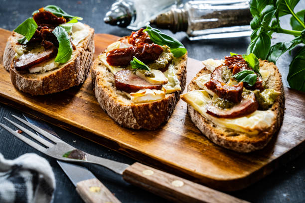 istock Mozzarella sandwich - crusty bread with sliced sausage,  mozzarella, basil and tomato salad on wooden table 1343690132