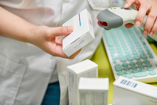 Pharmacist scanning barcode of medicine drug in a pharmacy drugstore.