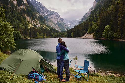 Embraced couple relaxing near a lake while camping