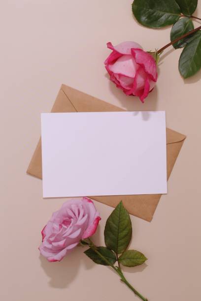 istock Styled feminine flat lay on pale peach background, top view. Minimal woman's desktop with blank page mock up, envelope, rose flowers. 1343712698