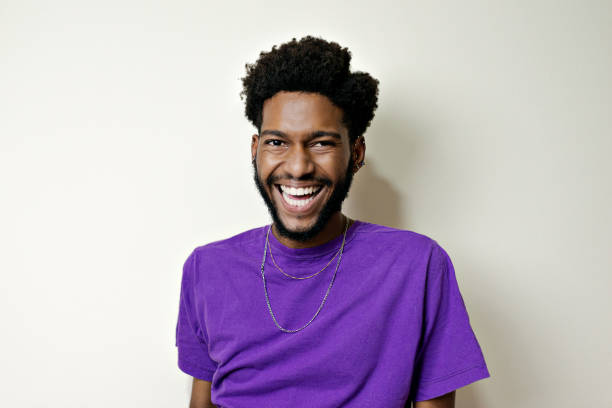 Portrait of young bearded man smiling looking at camera. Beauty with darker skin on a neutral background. afro man stock pictures, royalty-free photos & images