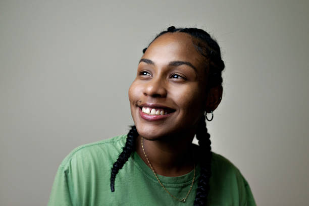 Portrait of young smiling woman with braids in her hair. Beauty with darker skin on a neutral background. lgbtqia culture photos stock pictures, royalty-free photos & images
