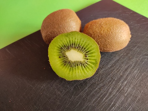 Photo of a close-up of a set of kiwis on a cutting board on a green background