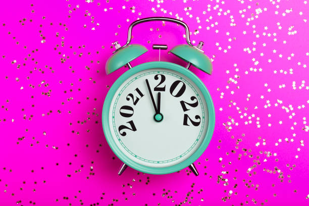 istock New Year 2022 background concept. 2021 changes to 2022 on an alarm clock on a pink background with festive glitter on New Year's Eve and Christmas. 1343732500