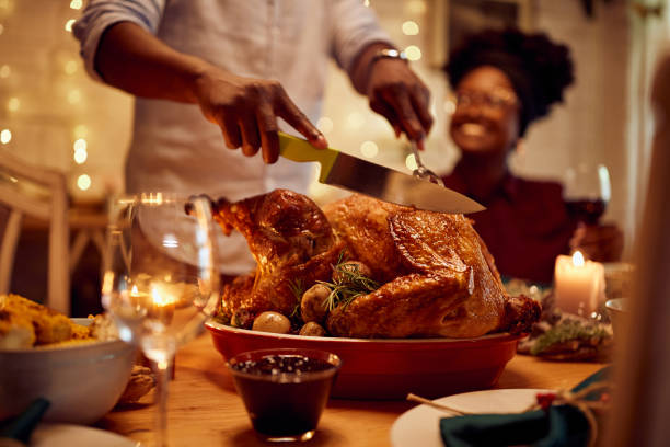 nahaufnahme eines afroamerikanischen mannes, der gerösteten thanksgiving-truthahn schnitzt. - roast turkey turkey thanksgiving holiday stock-fotos und bilder