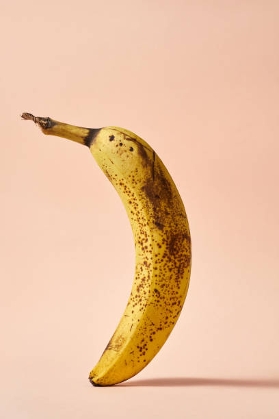 istock Banana creative poster with dark dots, overripe fruit on a pink background in flight. Consuming food wisely 1343748932