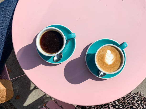 Morning coffees on pink table Morning coffees in tiffany color ceramic mugs with saucers on pink table. Black americano and latte. View from above coffee addict stock pictures, royalty-free photos & images