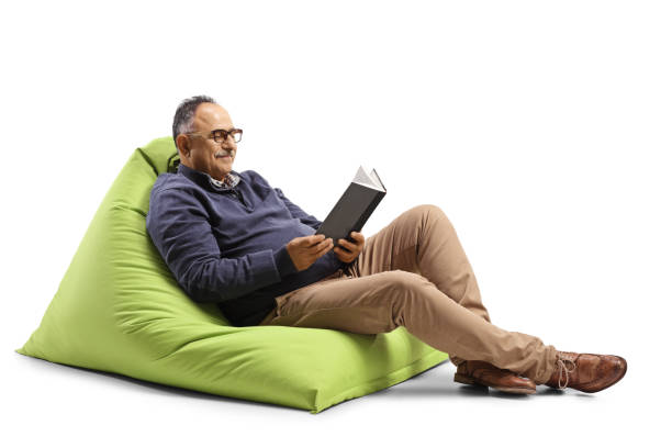 Mature man sitting on a green bean bag and reading a book