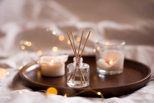 Hygge cozy home atmosphere Home perfume in glass bottle with wood sticks, scented burn candles  tray in bedroom close up. Aromatherapy cozy atmosphere lifestyle. Winter warm xmas season. life balance photos stock pictures, royalty-free photos & images