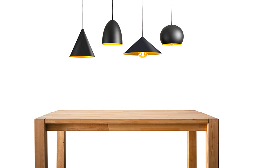 Front view of an empty wooden table with four black pendant lights hanging on it isolated on white background.