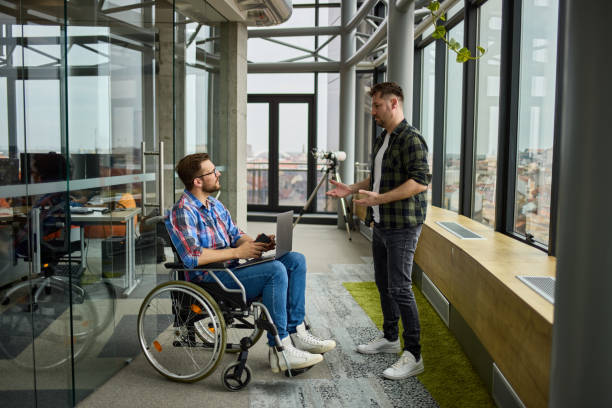 istock Disabled computer programmer discussing with male coworker in office hallway 1343765492