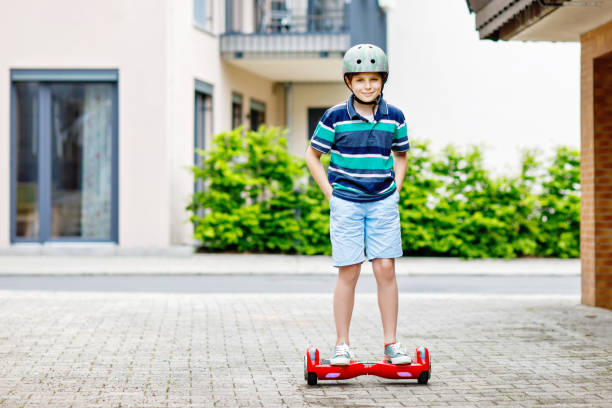 Active kid boy on hover board. Child driving modern balance hoverboard. Excercise and sports for children, outdoor activity for young kids.