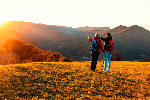 Enjoying in a nature Mother and daughter hikers on the mountain range. Enjoying in sunset. disabled person hiking outdoors stock pictures, royalty-free photos & images