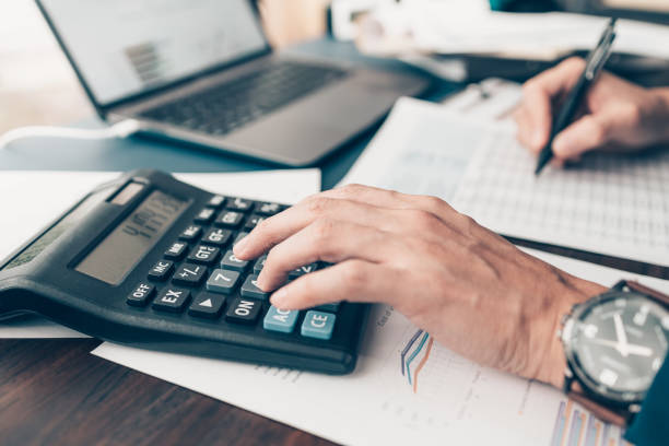 Financial businessman working on desk office using a calculator to calculate calculating corporate income tax data And analyzing charts of financial.  finance and accounting concept. stock photo